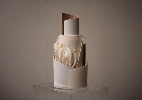 A neutral coloured, tiered cake with signature YiShi Cake ruffles